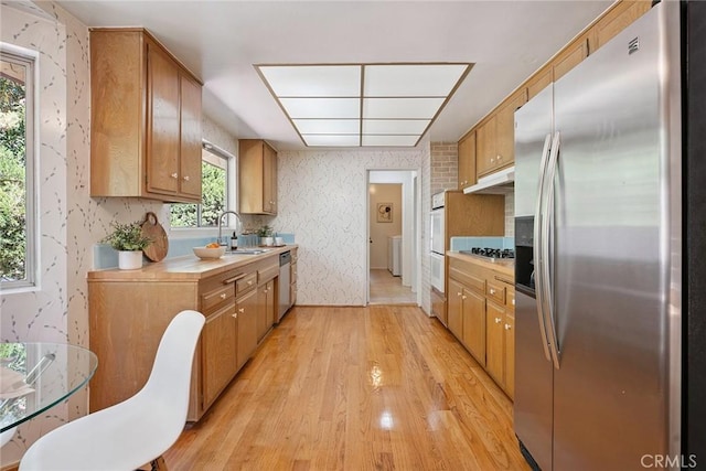 4241 Kingfisher Rd, Calabasas, CA 91302 - kitchen featuring appliances with stainless steel finishes, under cabinet range hood, wallpapered walls, light wood-type flooring, and light countertops