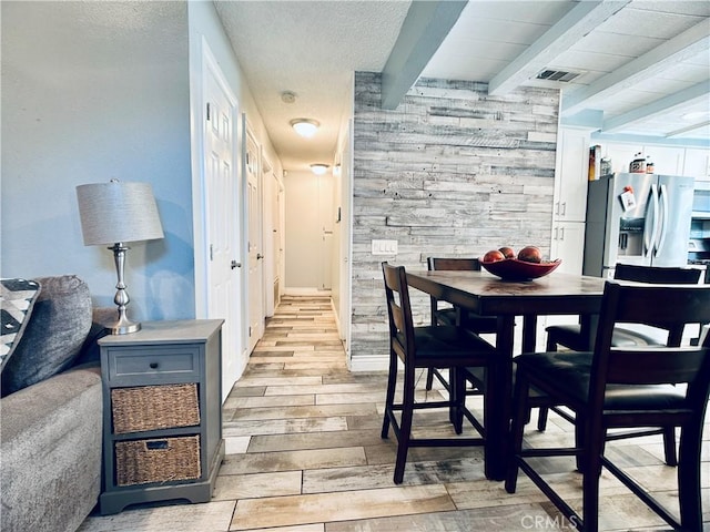 7707 Bolton Ave, Riverside, CA 92503 - dining room with beamed ceiling, light wood-style floors, wooden walls, and a textured ceiling