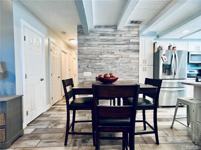 7707 Bolton Ave, Riverside, CA 92503 - dining space featuring wooden walls, beam ceiling, light wood-type flooring, and an accent wall