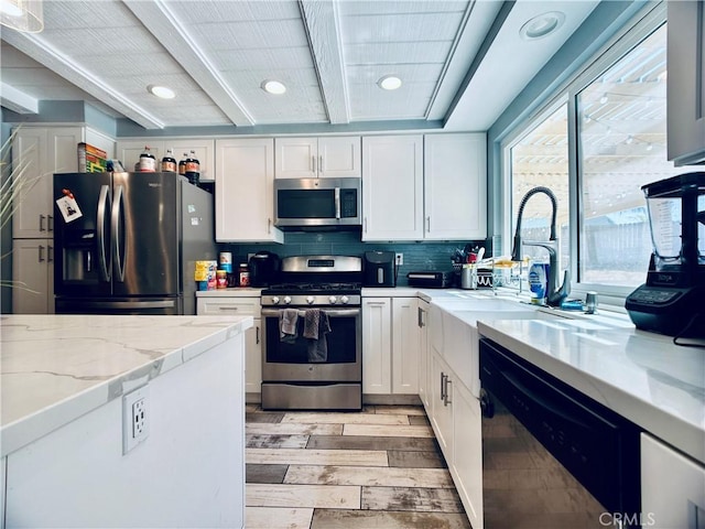 7707 Bolton Ave, Riverside, CA 92503 - kitchen with stainless steel appliances, light wood finished floors, white cabinets, beamed ceiling, and healthy amount of natural light