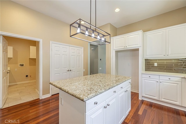 23785 Western Cedar Ct, Valencia, CA 91354 - kitchen featuring dark wood-type flooring, decorative backsplash, light stone counters, white cabinetry, and hanging light fixtures