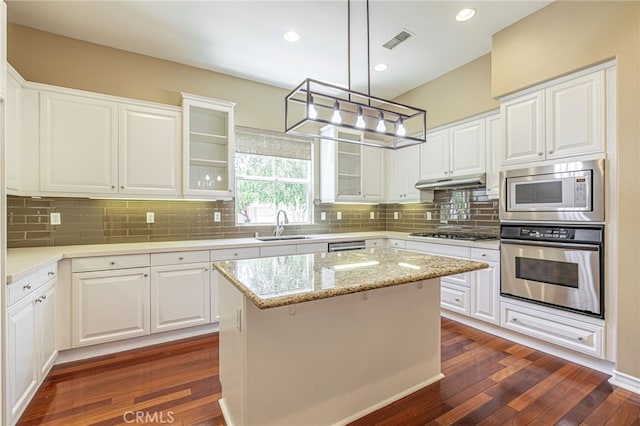 23785 Western Cedar Ct, Valencia, CA 91354 - kitchen with appliances with stainless steel finishes, glass insert cabinets, dark wood-type flooring, white cabinets, and tasteful backsplash