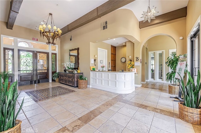 23785 Western Cedar Ct, Valencia, CA 91354 - entrance foyer featuring a towering ceiling, french doors, a chandelier, arched walkways, and stone tile floors