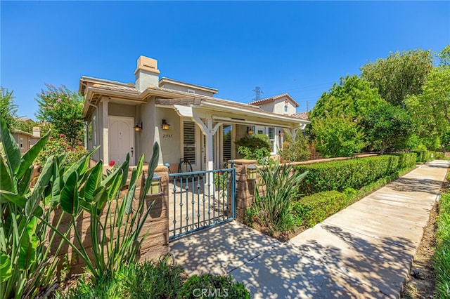 23785 Western Cedar Ct, Valencia, CA 91354 - view of front of property featuring a gate, a fenced front yard, a chimney, and stucco siding