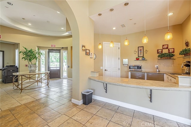 23785 Western Cedar Ct, Valencia, CA 91354 - kitchen with arched walkways, stainless steel microwave, recessed lighting, stone tile floors, and hanging light fixtures