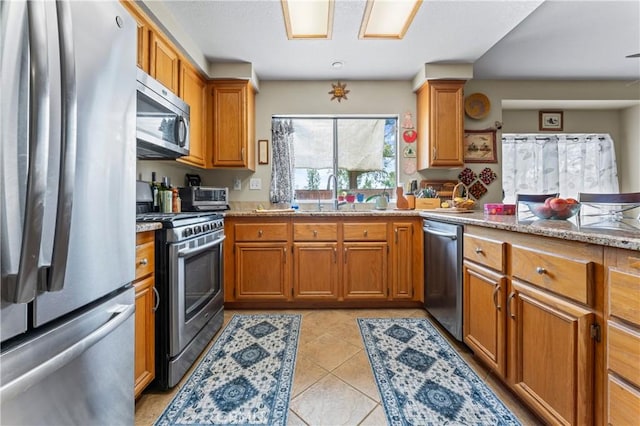 31941 Via Tafalla, Temecula, CA 92592 - kitchen with stainless steel appliances, brown cabinetry, light tile patterned floors, and light stone countertops