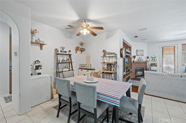 34722 Fairport Way, Yucaipa, CA 92399 - dining space with light tile patterned floors, a ceiling fan, a fireplace, and arched walkways