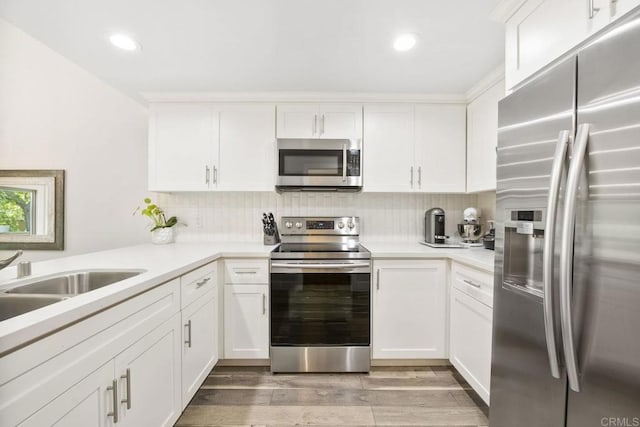 2352 Altisma Way Unit 13, Carlsbad, CA 92009 - kitchen featuring appliances with stainless steel finishes, white cabinets, decorative backsplash, light wood-style floors, and light countertops
