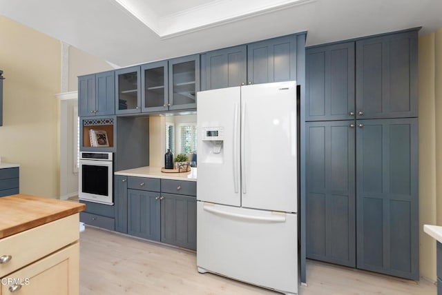 6357 Irena Ave, Camarillo, CA 93012 - kitchen with white fridge with ice dispenser, oven, light wood finished floors, glass insert cabinets, and crown molding
