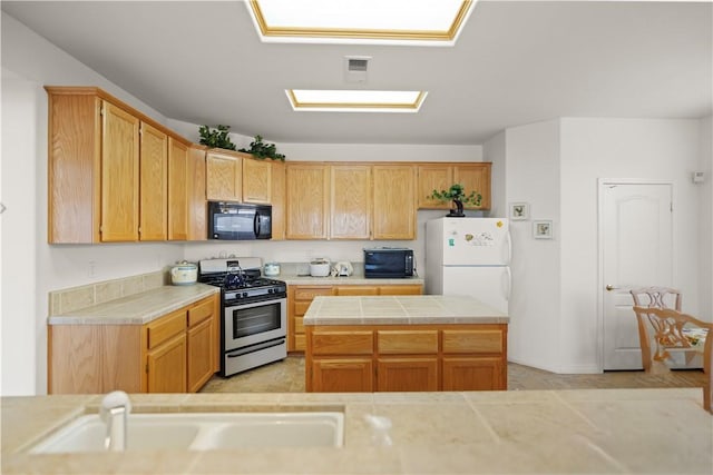 10527 Rose River Falls Ave, Bakersfield, CA 93312 - kitchen featuring black microwave, stainless steel gas stove, freestanding refrigerator, and a kitchen island