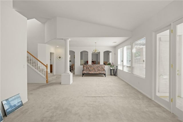 10527 Rose River Falls Ave, Bakersfield, CA 93312 - living room featuring light carpet, arched walkways, vaulted ceiling, stairway, and decorative columns