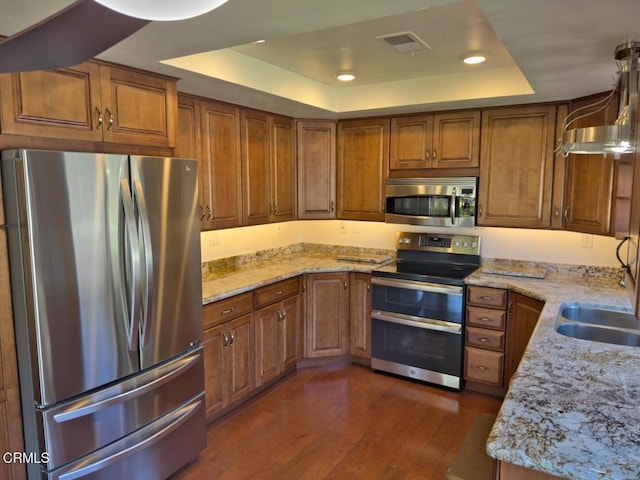 37134 Village 37, Camarillo, CA 93012 - kitchen featuring appliances with stainless steel finishes, a tray ceiling, brown cabinetry, and recessed lighting