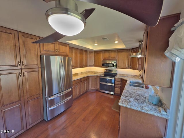 37134 Village 37, Camarillo, CA 93012 - kitchen with appliances with stainless steel finishes, brown cabinetry, dark wood-style flooring, a raised ceiling, and light stone counters