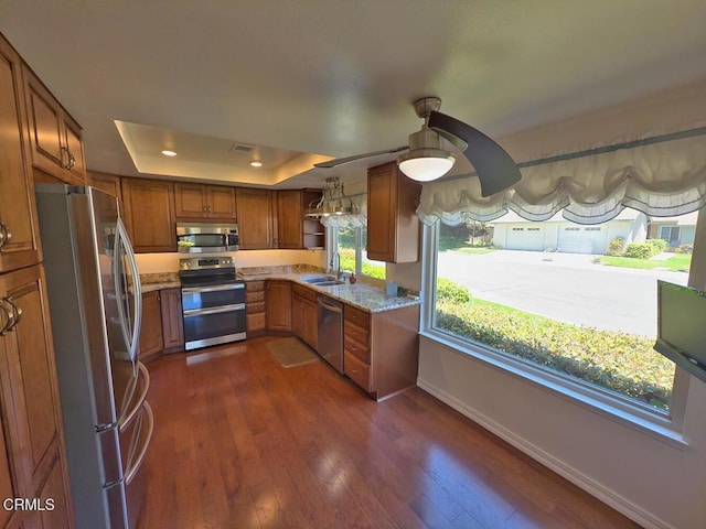 37134 Village 37, Camarillo, CA 93012 - kitchen with appliances with stainless steel finishes, brown cabinetry, a tray ceiling, and dark wood-style flooring