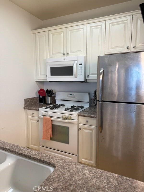 3120 Sepulveda Blvd Unit 409, Torrance, CA 90505 - kitchen featuring white appliances, dark stone counters, and white cabinetry