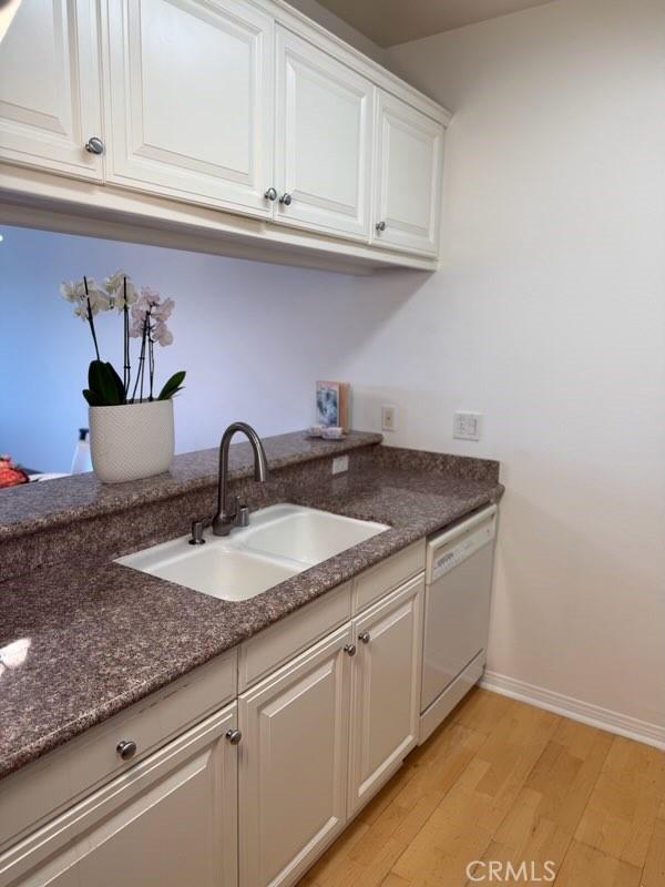 3120 Sepulveda Blvd Unit 409, Torrance, CA 90505 - kitchen with white dishwasher, light wood finished floors, white cabinetry, and dark stone countertops