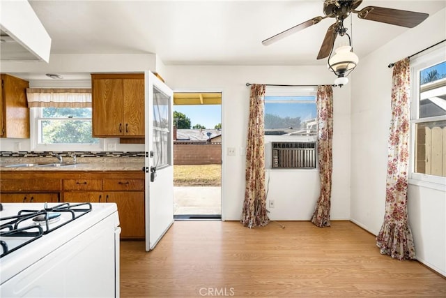 473 W Roberta Ave, Fullerton, CA 92832 - kitchen with brown cabinetry, white gas stove, light wood-type flooring, a ceiling fan, and cooling unit