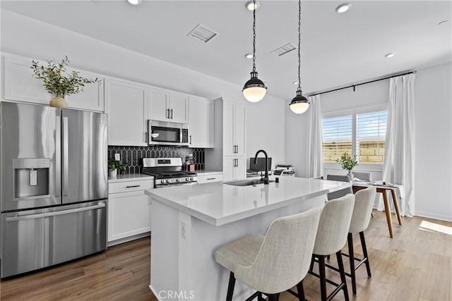 4408 S Grant Paseo, Ontario, CA 91762 - kitchen featuring stainless steel appliances, backsplash, white cabinetry, a breakfast bar area, and an island with sink
