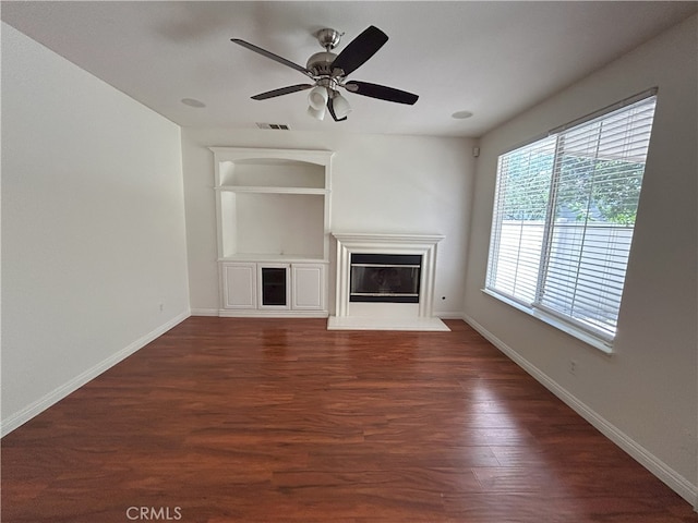 39877 Worthington Pl, Temecula, CA 92591 - unfurnished living room with built in shelves, a glass covered fireplace, dark wood finished floors, and a ceiling fan
