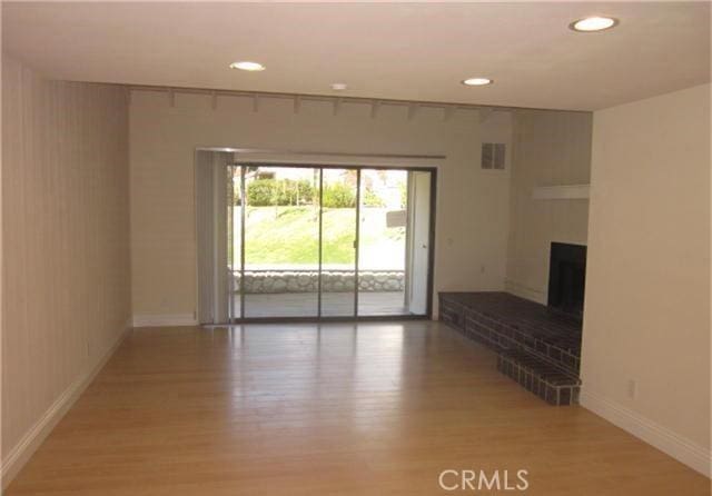 23551 Avenida La Caza Unit 129, Coto De Caza, CA 92679 - unfurnished living room featuring light wood-type flooring, recessed lighting, and a fireplace with raised hearth