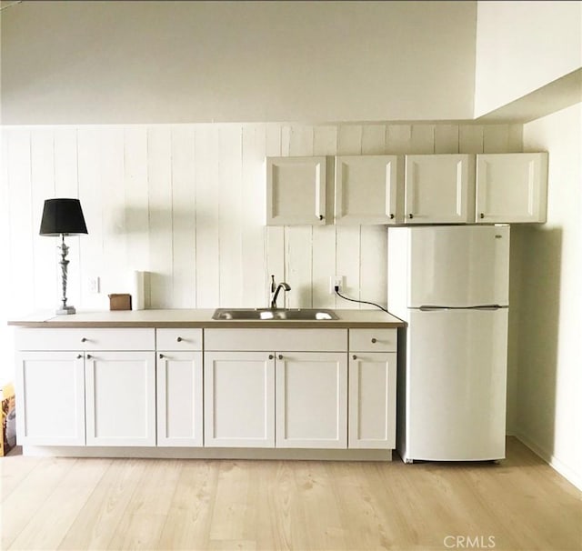 23551 Avenida La Caza Unit 129, Coto De Caza, CA 92679 - kitchen featuring freestanding refrigerator, light wood-style flooring, and white cabinetry