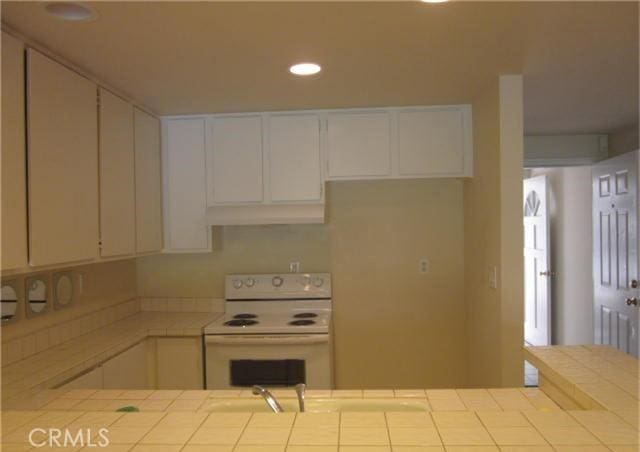 23551 Avenida La Caza Unit 129, Coto De Caza, CA 92679 - kitchen featuring electric stove, tile counters, white cabinetry, recessed lighting, and under cabinet range hood