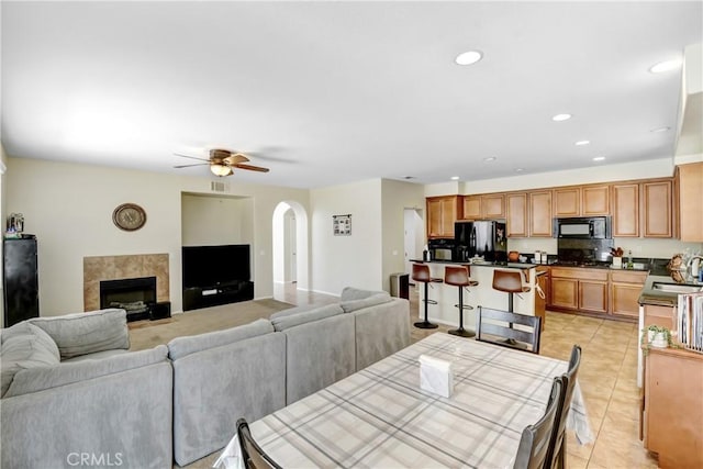 15247 Bandera Way, Victorville, CA 92394 - dining room with arched walkways, ceiling fan, light tile patterned flooring, recessed lighting, and a tile fireplace