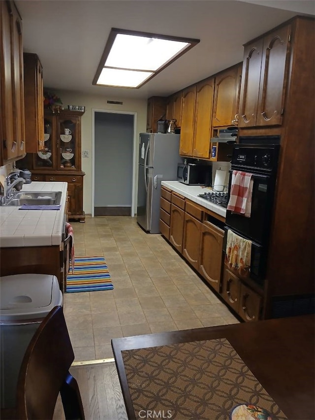 25521 17th St, San Bernardino, CA 92404 - kitchen featuring black appliances, tile countertops, light tile patterned floors, and a warming drawer