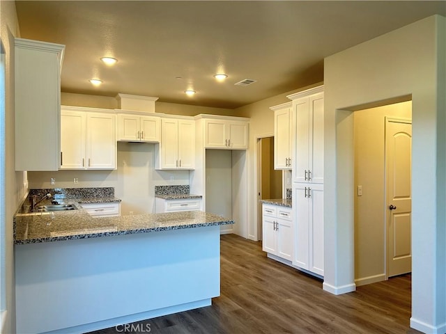 60 Sedona Dr, Merced, CA 95341 - kitchen with a peninsula, stone countertops, dark wood-type flooring, white cabinetry, and recessed lighting