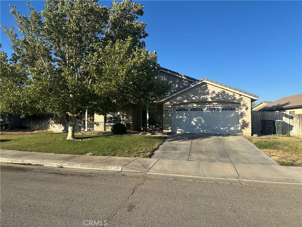 2248 Greenhill St, Rosamond, CA 93560 - obstructed view of property with an attached garage, driveway, and stucco siding