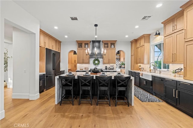 22388 Riverstream Ct, Saugus, CA 91350 - kitchen featuring wall chimney exhaust hood, arched walkways, high end fridge, dishwasher, and a breakfast bar