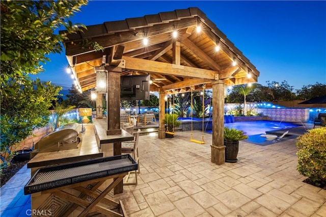22388 Riverstream Ct, Saugus, CA 91350 - patio at night featuring exterior kitchen, a gazebo, an outdoor bar, an outdoor pool, and a patio