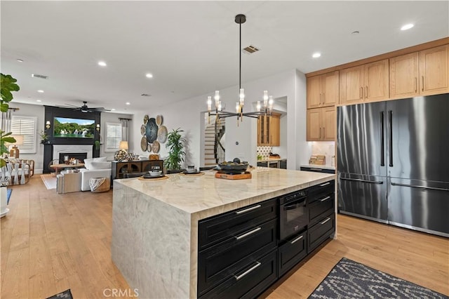 22388 Riverstream Ct, Saugus, CA 91350 - kitchen featuring stainless steel fridge, light wood-style floors, a chandelier, a warm lit fireplace, and ceiling fan