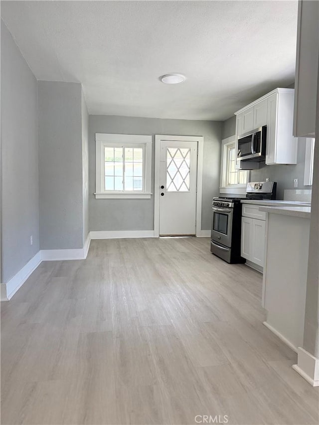 1271 N K St, San Bernardino, CA 92411 - kitchen featuring stainless steel appliances, white cabinets, light wood finished floors, and light countertops