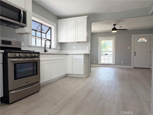 1271 N K St, San Bernardino, CA 92411 - kitchen with appliances with stainless steel finishes, light countertops, light wood-style floors, a ceiling fan, and white cabinets