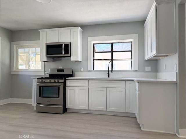 1271 N K St, San Bernardino, CA 92411 - kitchen featuring stainless steel appliances, light wood-style floors, light countertops, and white cabinets
