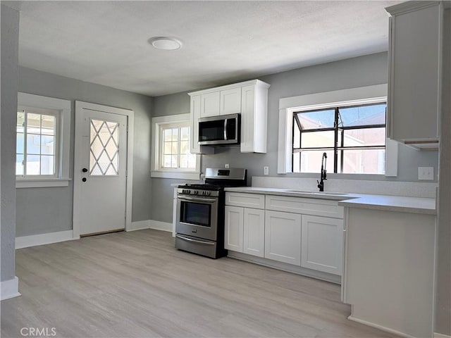 1271 N K St, San Bernardino, CA 92411 - kitchen featuring appliances with stainless steel finishes, light wood finished floors, light countertops, and white cabinetry