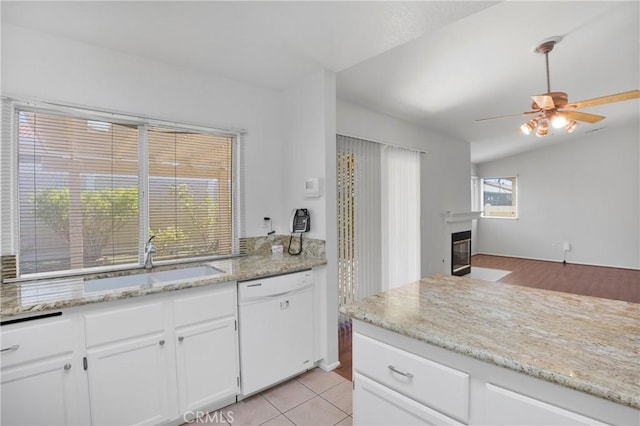 14183 Gale Dr, Victorville, CA 92394 - kitchen with white dishwasher, a fireplace with flush hearth, ceiling fan, white cabinets, and light stone countertops