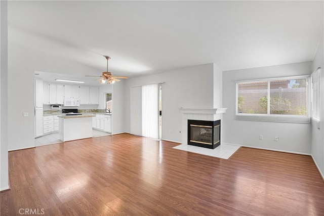 14183 Gale Dr, Victorville, CA 92394 - unfurnished living room with a tile fireplace, a ceiling fan, light wood-type flooring, and vaulted ceiling