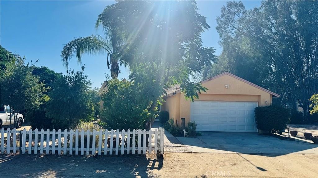 31191 Murrieta Rd, Menifee, CA 92584 - obstructed view of property with driveway, stucco siding, and a garage