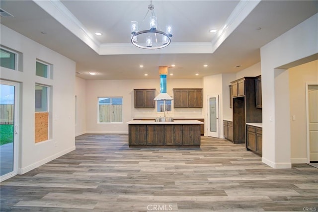 210 Kelly Ct, Atwater, CA 95301 - kitchen featuring a tray ceiling, a chandelier, ornamental molding, light countertops, and wall chimney range hood