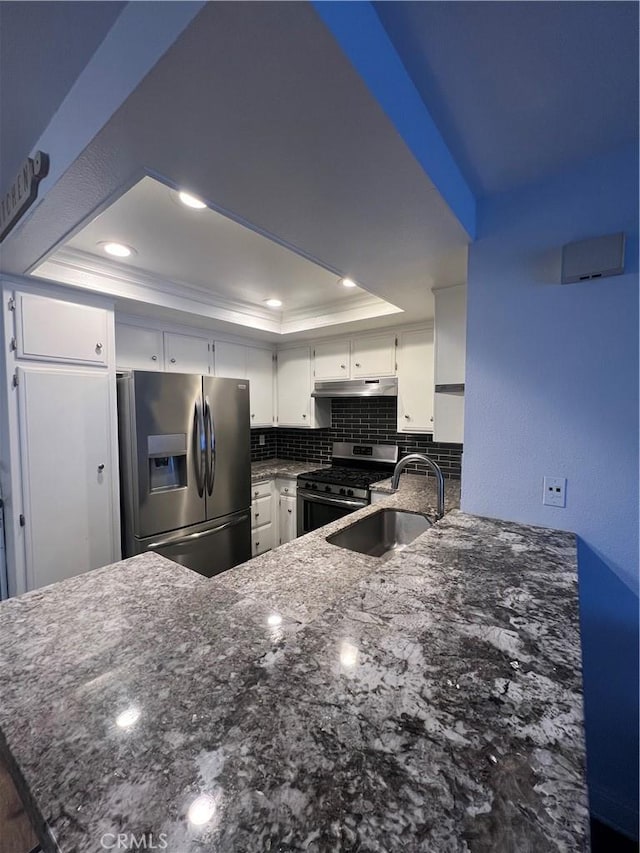 24297 El Pilar, Laguna Niguel, CA 92677 - kitchen with appliances with stainless steel finishes, a raised ceiling, a peninsula, dark stone countertops, and white cabinets