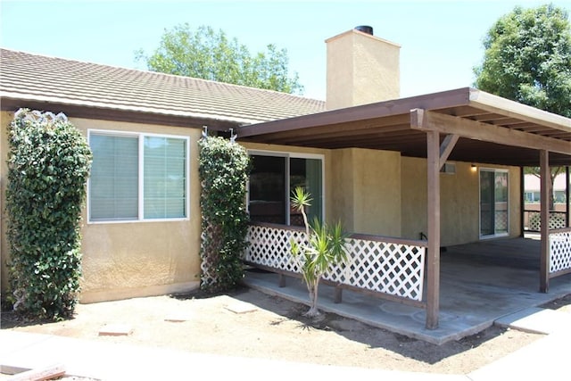 10768 William Ave, Bloomington, CA 92316 - doorway to property with a chimney, stucco siding, and a patio
