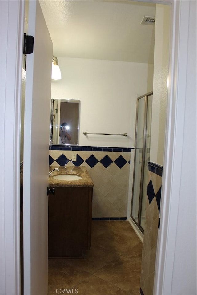 10768 William Ave, Bloomington, CA 92316 - full bath featuring tile walls, vanity, a shower stall, tile patterned flooring, and a wainscoted wall