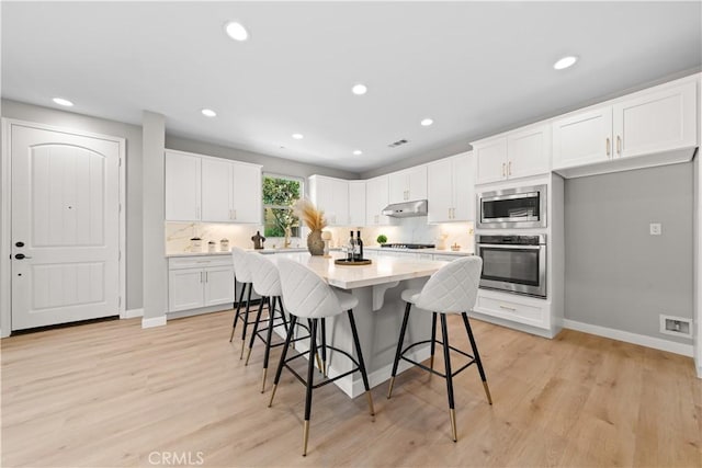 22 Lomada St, Rancho Mission Viejo, CA 92694 - kitchen featuring appliances with stainless steel finishes, white cabinetry, a breakfast bar area, recessed lighting, and under cabinet range hood