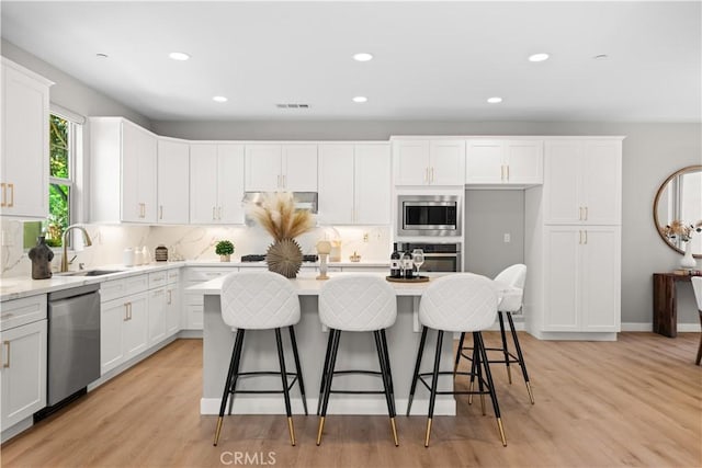 22 Lomada St, Rancho Mission Viejo, CA 92694 - kitchen featuring appliances with stainless steel finishes, a center island, white cabinets, recessed lighting, and light wood-style flooring