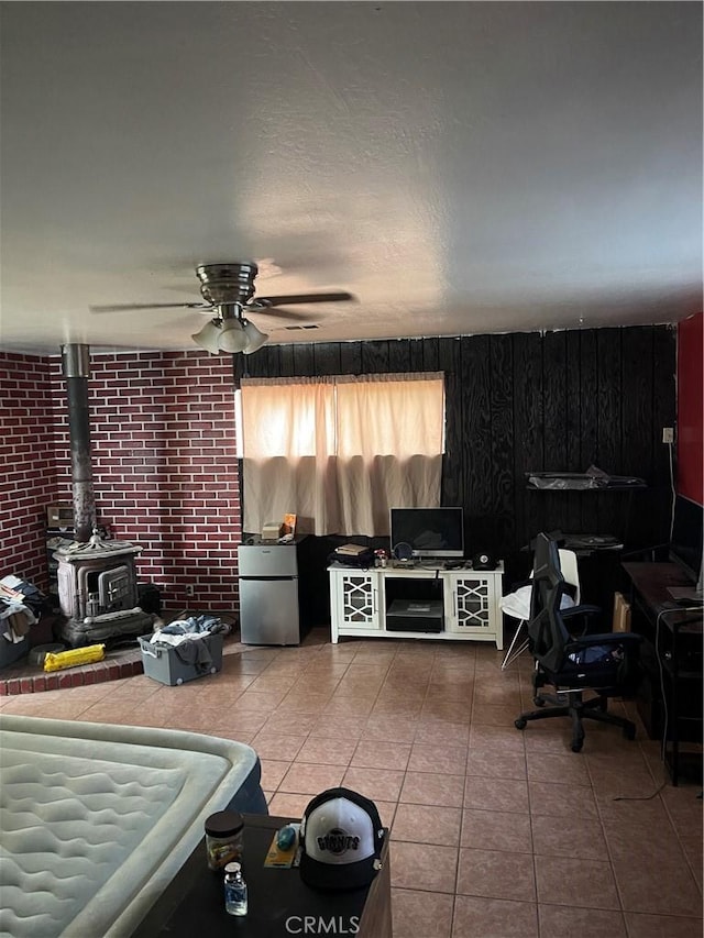 537 Drakeley Ave, Atwater, CA 95301 - living room with a wood stove, tile patterned flooring, a ceiling fan, and wood walls