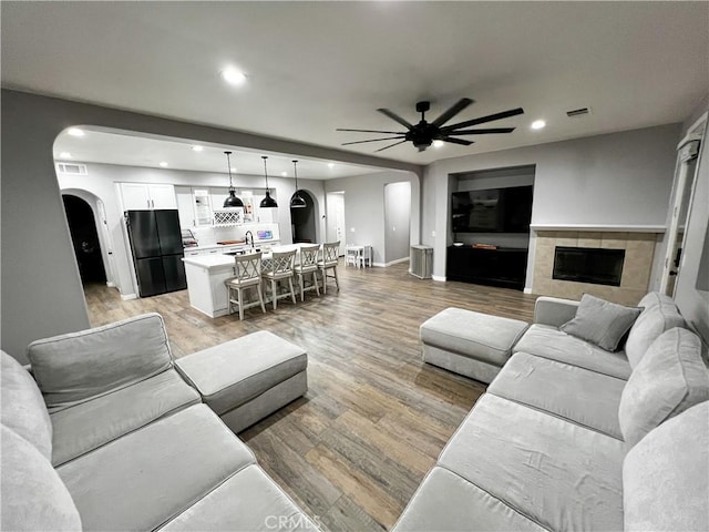 5834 Gem Ct, Lancaster, CA 93536 - living room with arched walkways, ceiling fan, light wood-style flooring, recessed lighting, and a fireplace