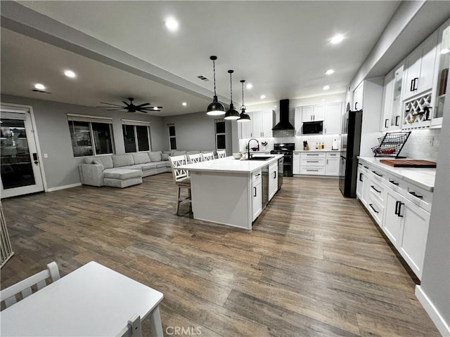 5834 Gem Ct, Lancaster, CA 93536 - kitchen with black appliances, a breakfast bar area, open floor plan, wall chimney exhaust hood, and recessed lighting