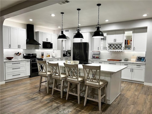 5834 Gem Ct, Lancaster, CA 93536 - kitchen with wall chimney range hood, black appliances, tasteful backsplash, a kitchen bar, and recessed lighting